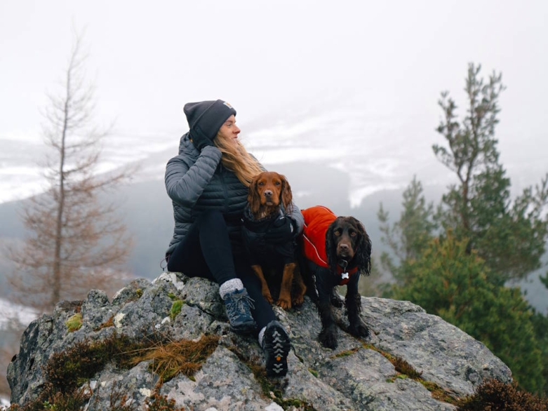 Frau mit 2 Hunden auf einem Felsen