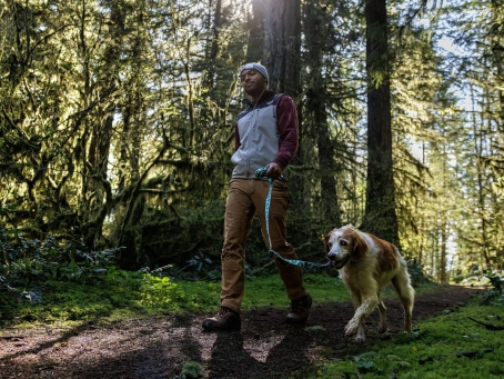 Mann mit angeleintem Hund im Wald